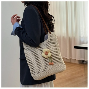 Dettaglio borsa tote beige all'uncinetto con ciondolo girasole 3D e manici in pelle