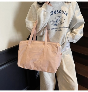 Detailed macro view of pink nylon travel tote with printed slogan and side pockets