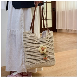 Dettaglio della borsa tote in tessuto traforato con fiore giallo e manici in pelle marrone