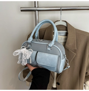 Close-up of light blue bowling bag featuring dual pockets and lace pearl pendant