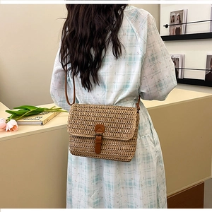 Détail d'un sac bandoulière en paille tressée avec bandoulière en cuir sur robe d'été