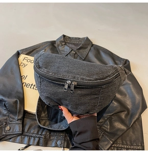 Close-up of black denim chest bag with dual metal zippers and washed fabric texture