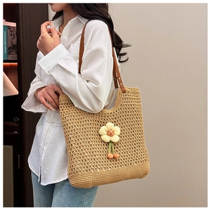 Dettaglio della borsa tote in paglia intrecciata con girasole e manici in pelle