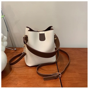 Detail of retro cream and brown bucket bag with dual straps on a wooden table