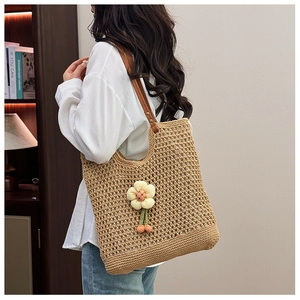 Dettaglio della borsa tote in paglia intrecciata con tracolla e ciondolo girasole