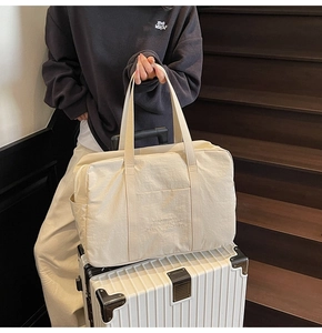 Large capacity canvas travel tote bag with embroidery placed on a white suitcase