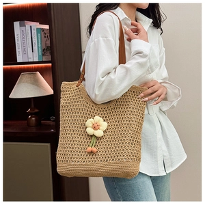 Dettaglio borsa tote in paglia intrecciata traforata con decorazione floreale 3D e tracolla