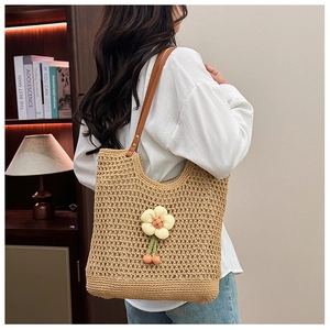 Dettaglio della borsa tote intrecciata con fiore 3D giallo e manici in pelle marrone