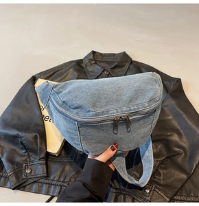 Detail of light blue denim waist bag showing faded texture and dual zipper closure