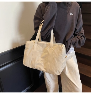 Close-up of lightweight off-white nylon tote bag showing textured fabric and side pockets