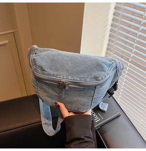 Close-up of light blue denim chest bag showing vintage wash texture and metal double zippers