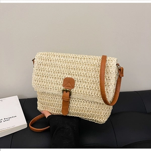 Détail du sac bandoulière en paille beige avec lanières en cuir brun et boucle rétro
