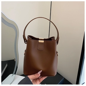 Detailed shot of brown PU leather bucket bag with elegant golden rectangular clasp
