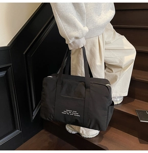 Close-up of black high-density fabric travel tote with white slogan and wide straps