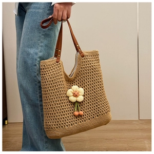 Dettaglio della borsa tote all'uncinetto con fiore in tessuto e manici in pelle