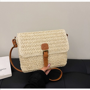 Détail de la texture tressée et de la bandoulière en cuir de ce sac rétro en paille