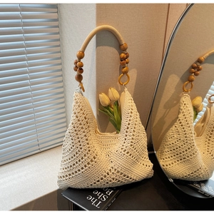 Detail der cremefarbenen Häkeltasche mit Lochmuster und Griffen aus Holzperlenverzierung