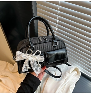 Detail of tweed crossbody bag featuring pearl lace bow charm and polished leather trim