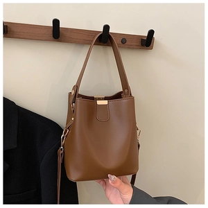 Close-up of caramel leather bucket bag with gold metal buckle and adjustable straps