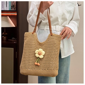 Dettaglio della borsa tote a rete intrecciata con fiori 3D e ciondolo a ciliegia