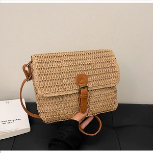Détail d'un sac bandoulière vintage en paille avec lanière en cuir brun et boucle