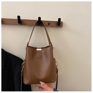 Detailed view of caramel bucket bag with gold clasp and adjustable strap on a hanger