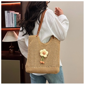 Dettaglio della borsa a rete intrecciata con fiori decorativi e tracolla in pelle marrone