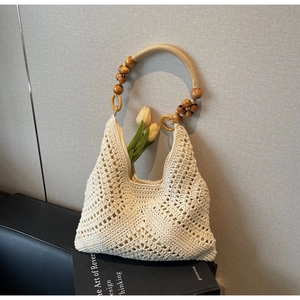 Detail der Bohème-Strohtasche mit Holzperlengriffen und hohlen Häkelmustern im Detail