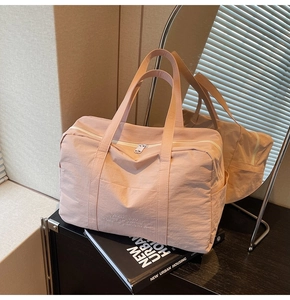 Detail of pink nylon travel bag featuring reinforced handles and side storage pocket