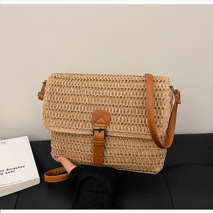 Gros plan du sac en paille tressée avec rabat en cuir marron et boucle en bronze vintage