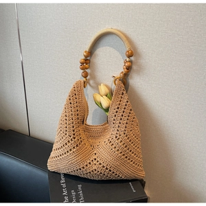Detail der hohlen Häkeltextur der khakifarbenen Strohtasche mit Holzperlen griff und Tulpen