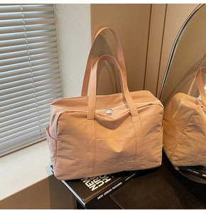 Detail of soft pink quilted nylon travel bag featuring reinforced dual handles and zipper