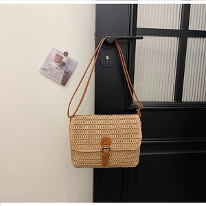 Détail d'un sac carré en paille tissée avec boucle en cuir brun et fine bandoulière