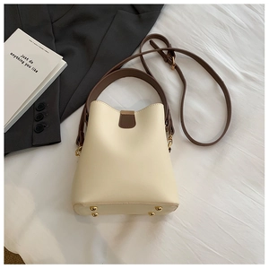 Detailed view of cream bucket bag with brown straps and golden anti-wear base studs