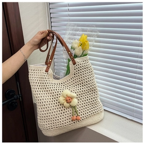 Dettaglio della borsa tote a rete intrecciata con manici in pelle e pendente floreale