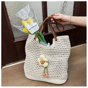 Dettaglio della borsa tote in rete beige con decorazione floreale 3D e manici in pelle