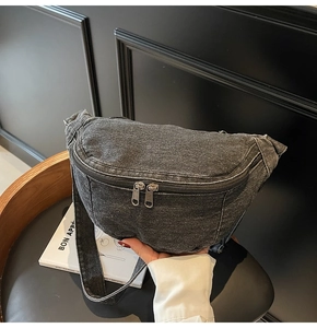 Detail of black washed denim chest bag with durable texture and dual metal zippers
