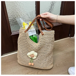 Dettaglio della borsa tote all'uncinetto con fiori 3D e manici in pelle marrone