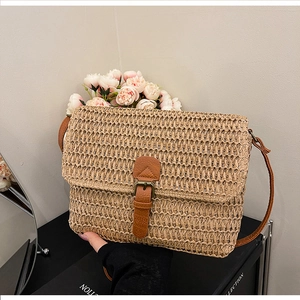 Détail de la texture d'un sac en paille avec lanière en cuir et boucle en métal