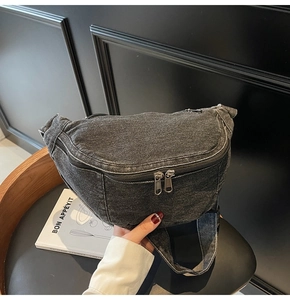 Detailed view of washed denim chest bag in dark gray with dual zippers and wide strap