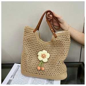 Dettaglio della borsa tote intrecciata beige con accenti floreali e manici in pelle marrone
