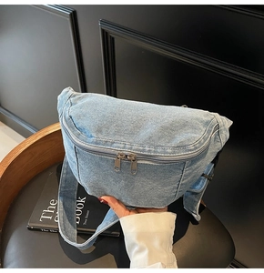 Close-up of light blue denim chest bag with durable dual metal zippers and wide strap