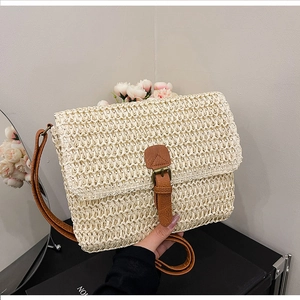 Gros plan d'un sac bandoulière en paille tressée vintage avec sangle en cuir marron