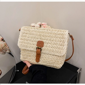 Détail du sac bandoulière en paille tressée avec sangle en cuir brun et boucle métal
