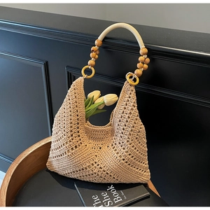 Details des hohlen geometrischen Strickmusters und der Holzperlenriemen der Strohtasche