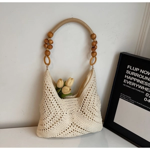 Nahaufnahme der Stroh-Tasche mit Lochmuster und Details zum Holzperlen-Griff