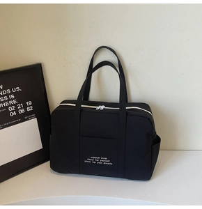 Detailed view of black canvas tote bag with white zipper and inspirational text