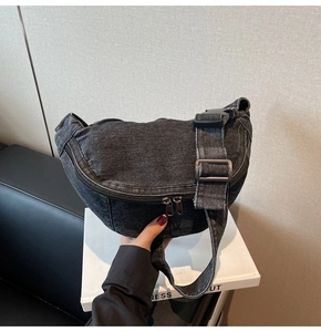 Close-up of black washed denim chest bag with double zipper and buckle strap detail