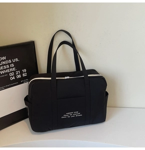 Close-up of large black tote bag with white zippers and functional side storage pocket