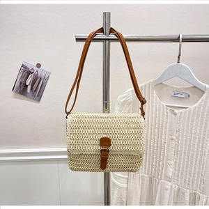 Détail du sac bandoulière en paille beige avec sangle en cuir marron et fermoir à boucle